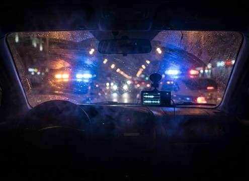 Muffled police siren heard through a car window interior POV